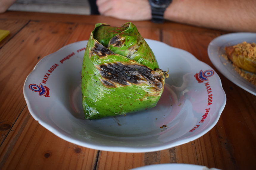 nasi bakar (Indonesian grilled rice) served on plate, still wrapped in banana leaf