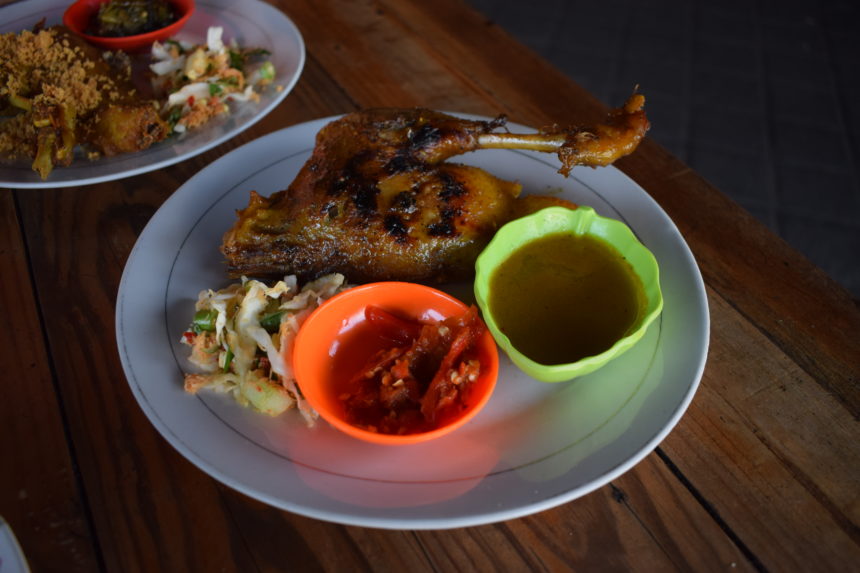 bebek bakar (Indonesian crispy duck) on a plate with urap and sambal bawang