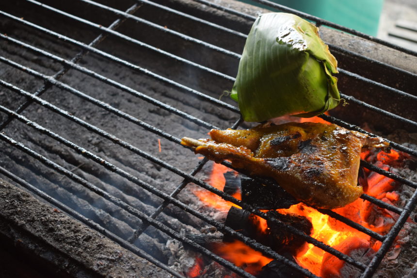 bebek goreng (Indonesian grilled duck) and nasi bakar on grill over flaming charcoal
