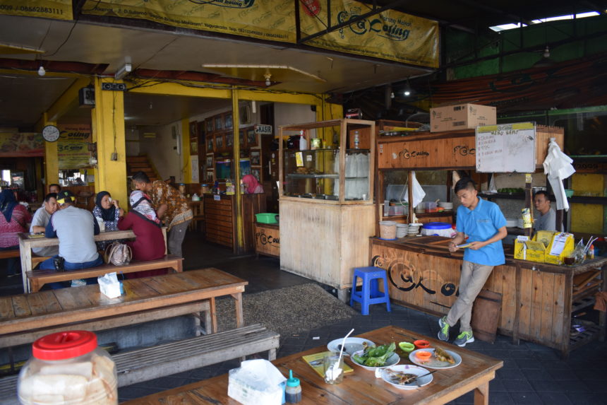 Interior of Warung Makan Cak Koting restaurant in Yogyakarta (Jogja) with waiter leaning on grill