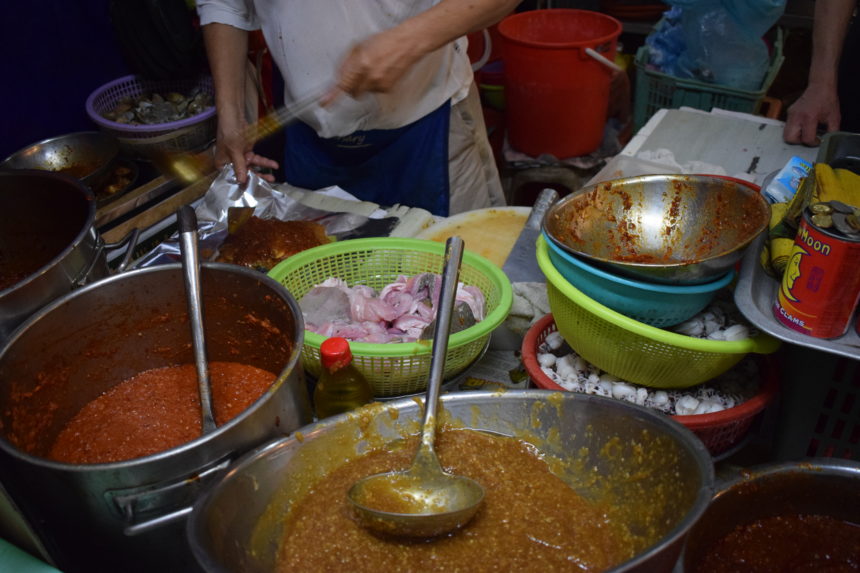 man constructing parcel by spooning sambal over raw fish