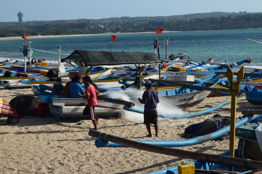 Fisherman with boat and net on Jimbaran Beach next to the fish market