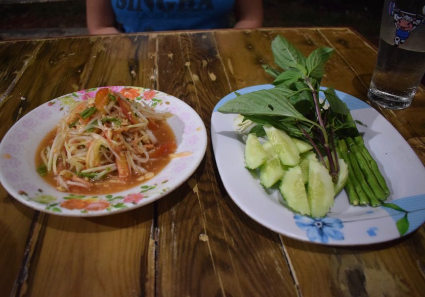 som tam served with a side plate of crunchy raw vegetables and thai basil