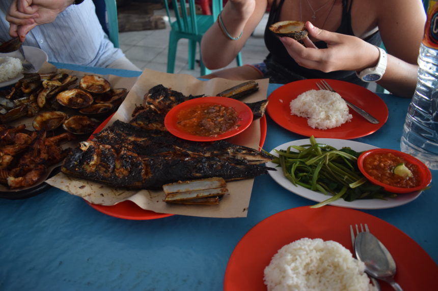 Eating a seafood feast with hands at Jimbaran Market