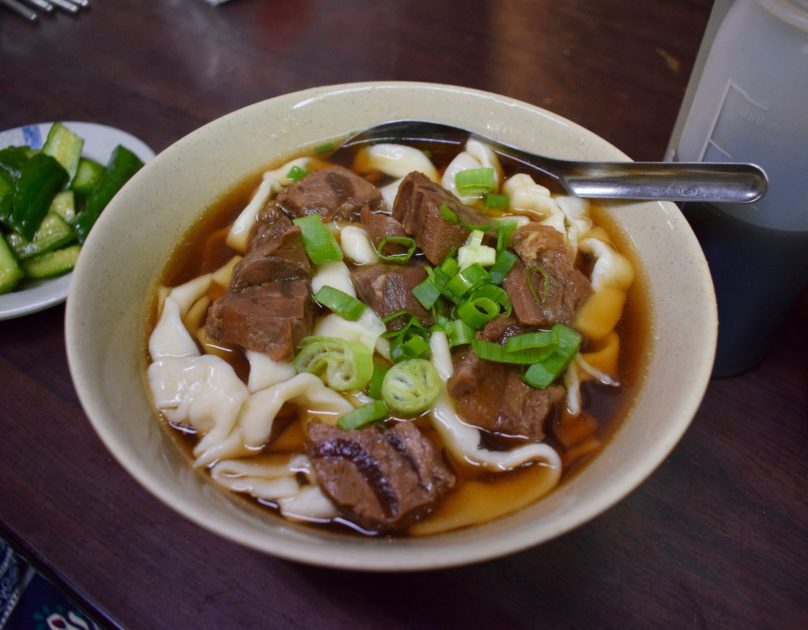 bowl of beef noodles with no condiments added topped with spring onions