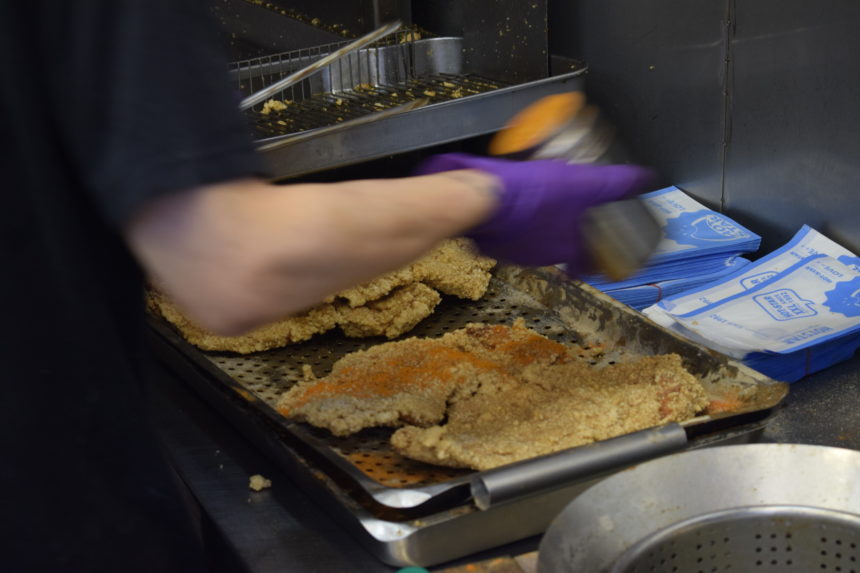 Man shaking seasoning over Hot Star Large Fried Chicken 