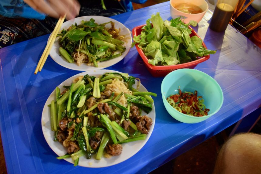 The spread of food at Phở Xào Ba Thanh Béo with pho xao, pickles, bowl of herbs and pot of vinegar