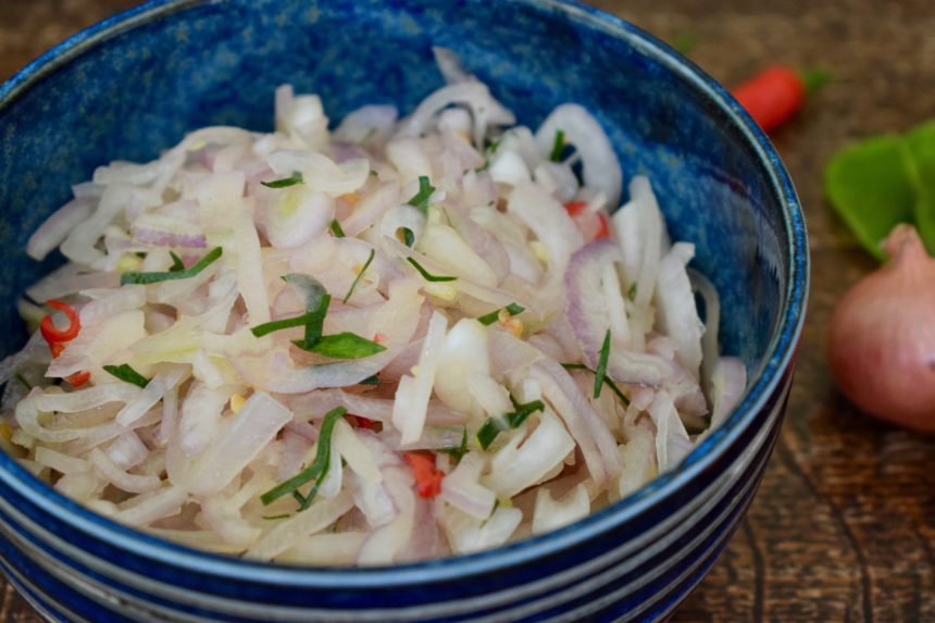 Close-up of sambal bali showing shallot slices and thin pieces of kaffir lime and chilli