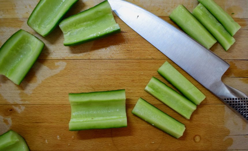 Chopping the cored cucumber into 1.5cmx6cm batons on a wooden chopping board