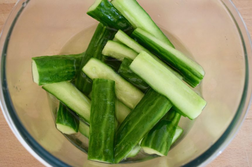 Cucumber batons in bowl after first stage of curing showing liquid to be drained off