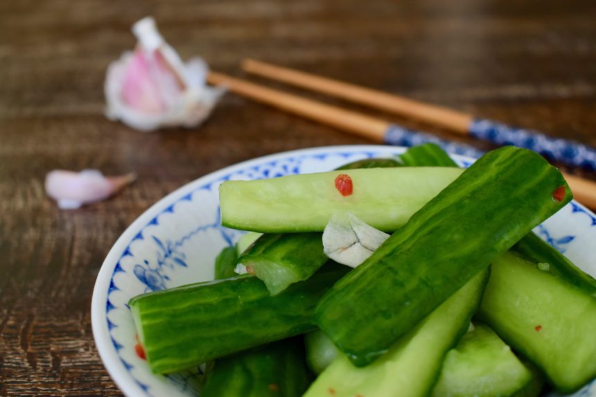 Close-up of Taiwanese spicy cucumber salad showing chopped chilli and garlic with chopsticks and garlic in background
