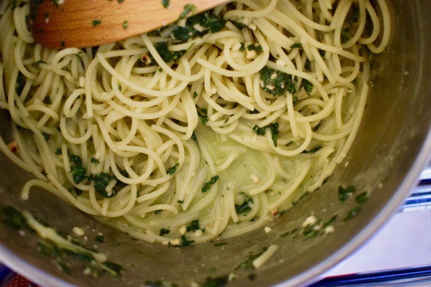 A pool of creamy-looking sauce at the bottom of the the pan containing thai basil pesto pasta