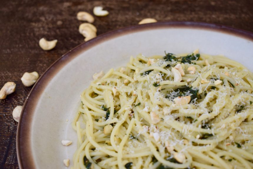 Close-up of thai basil pasta with scattered cashew nuts in the background