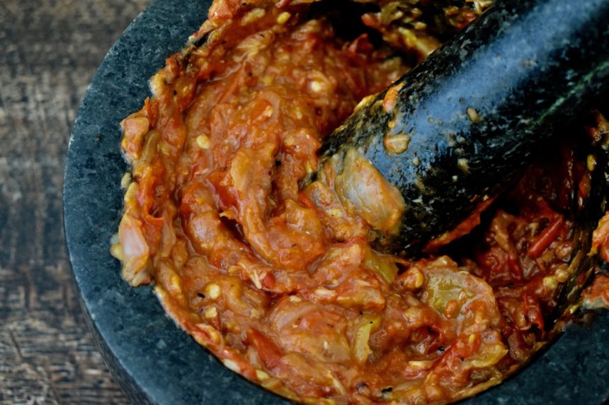 Close-up of my sambal terasi in mortar with pestle resting in it showing rough texture required