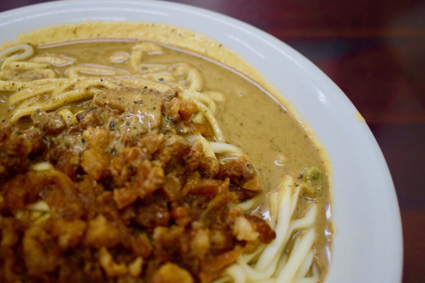 Close-up of Taiwanese sesame noodles showing glossy Chinese sesame sauce and braised pork belly pieces