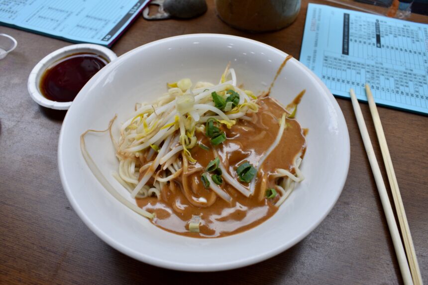 A bowl of ma jiang mian noodles ordered at ba fang yun ji in Taipei on a table with chopsticks and menus