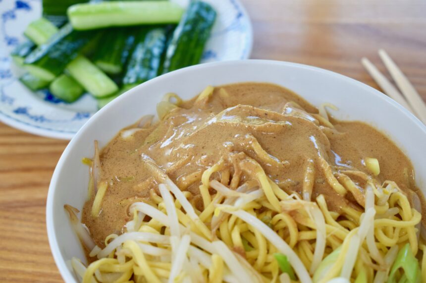 Close up of Taiwanese sesame noodles (ma jiang mian) with Taiwanese cucumber salad in the background