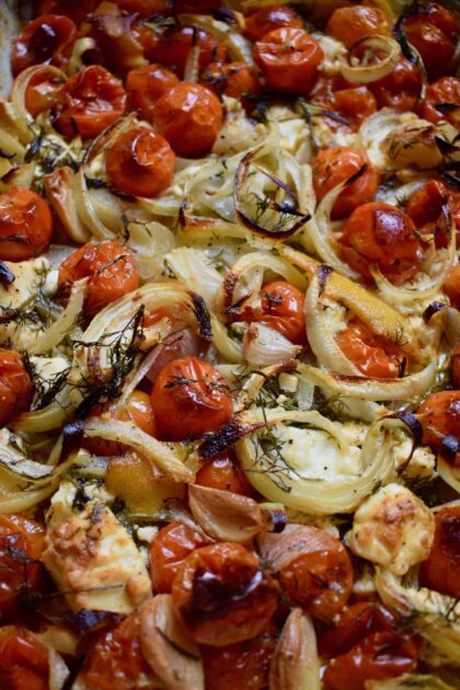 The initial vegetable mixture for the Mediterranean rice after being roasted in the oven showing charred tomatoes onions and feta