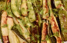 Close-up of charred roasted courgette chunks covered with summery dressing